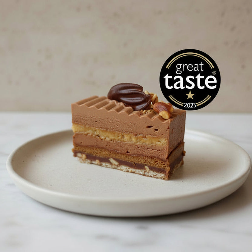 Discover our award-winning Peanut Praline Cake, layered with chocolate ganache, nutty sponge, praline crunch, and caramelised peanut brittle. Collection only from North London.