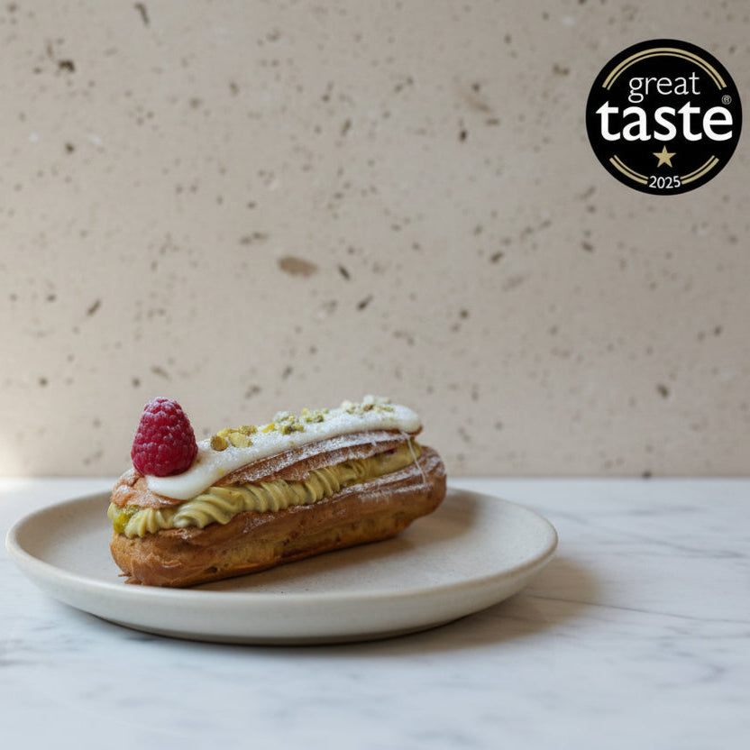Pastry with raspberry and cream on a plate, featuring the Great Taste 2025 logo.