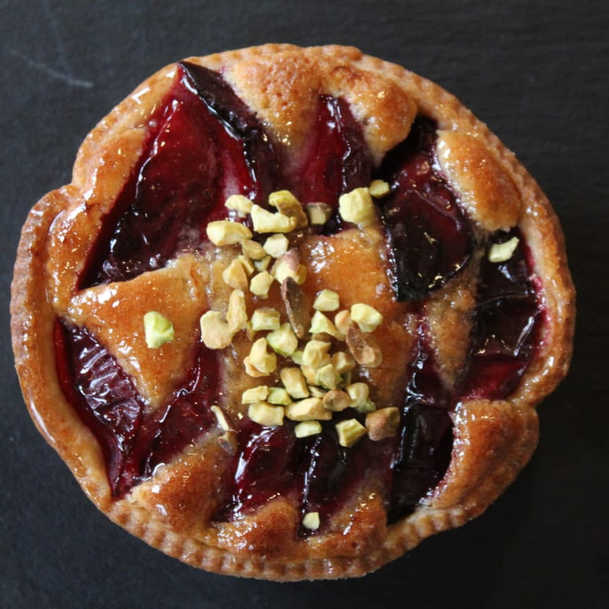 Plum and pistachio frangipane tart with golden pastry, almond filling, glazed plums, and chopped pistachios, Great Taste Award 2022, handmade in North London