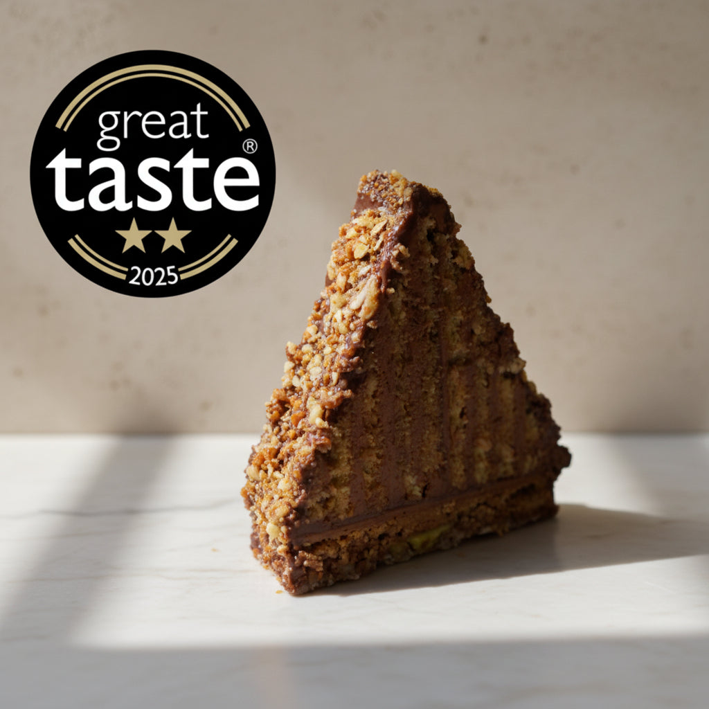 Mountain Cake with pecan and almond jaconde sponge layered with Belgian chocolate mousse. It's coated in honey chocolate ganache, handcrafted in North London