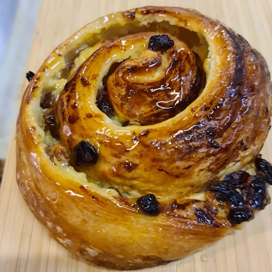 Four handmade Pain au Raisins pastries filled with vanilla custard and golden raisins, glazed and golden, made with 100% butter in North London