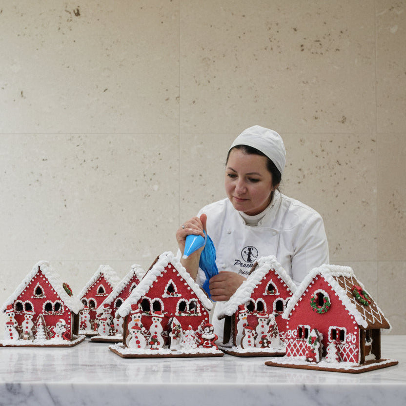 Baker decorating gingerbread houses in a kitchen setting