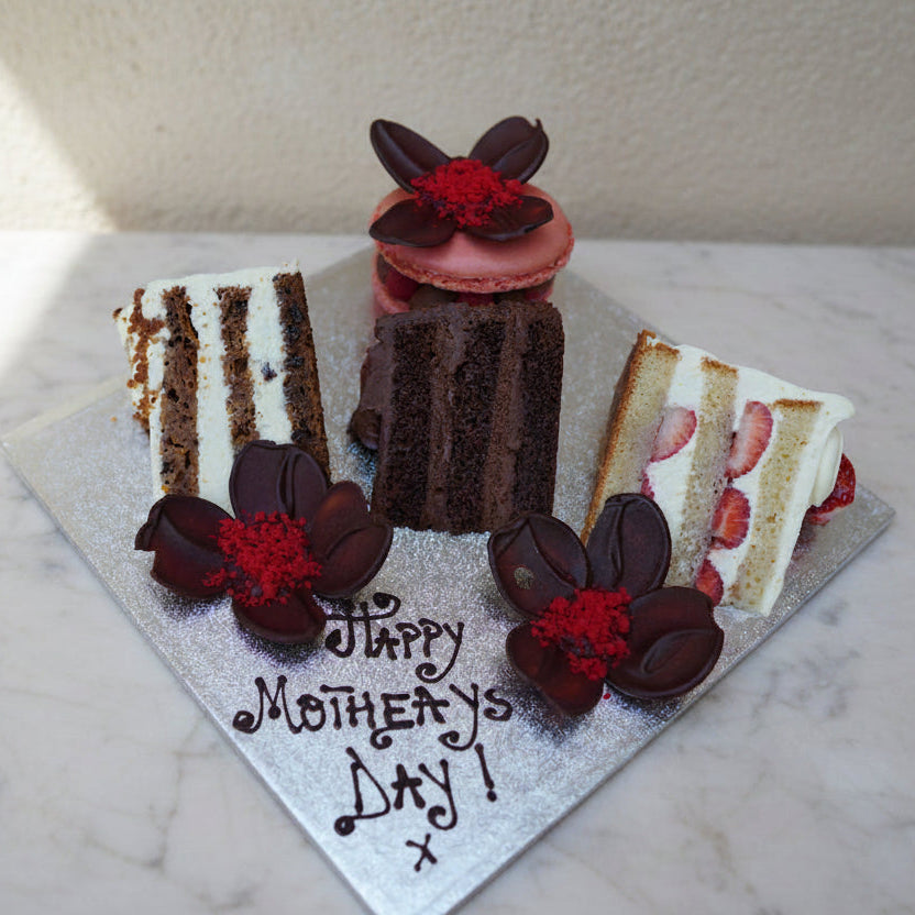 Small birthday cake with chocolate flowers and 'Happy Birthday, Dan!' message on a wooden surface