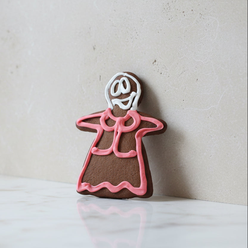 Gingerbread cookies shaped like a person with pink icing on a wooden surface