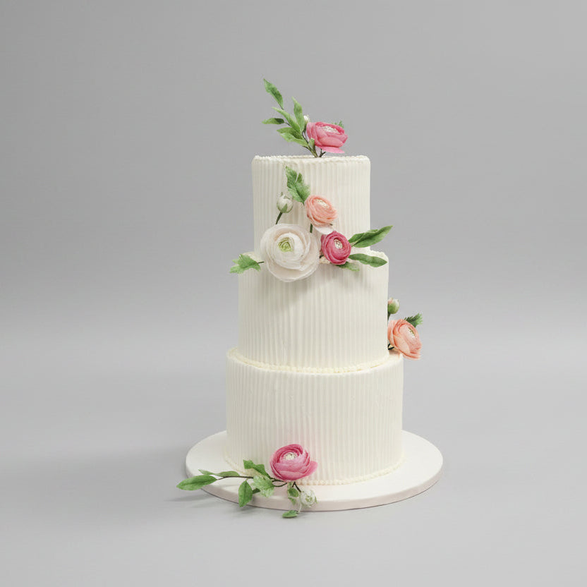 Three-tiered Medovik wedding cake with sugar floral decorations on a gray background