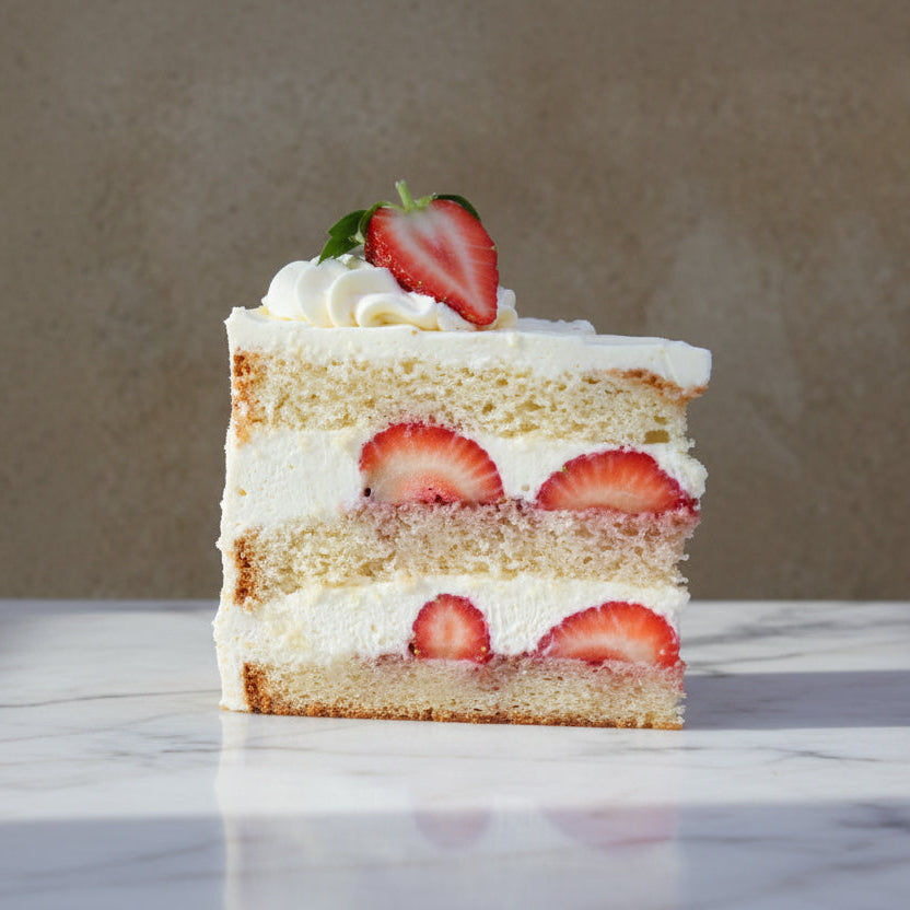 Slice of Victoria Celebration Cake with layers of fresh strawberries and whipped cream cheese