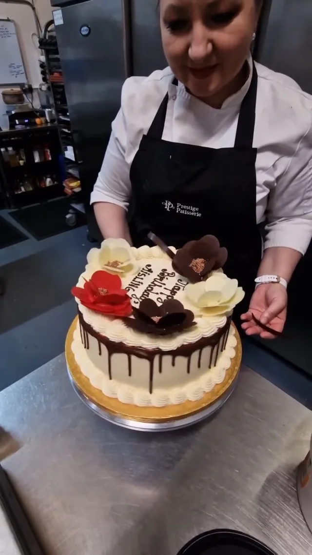 Every bespoke cake deserves a beautiful finish. 🌸  Watch Geanina carefully place our handmade chocolate flowers onto this celebration cake, adding the final touches before it leaves the patisserie.  Every flower is handcrafted in-house and positioned by hand to create a truly unique design.  At Prestige Patisserie, it's the little details that make every cake special.  #ChocolateFlowers #CakeDecorating